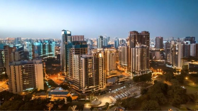 Aerial view of illuminated high-rise residential and commercial buildings in Gurgaon at dusk.